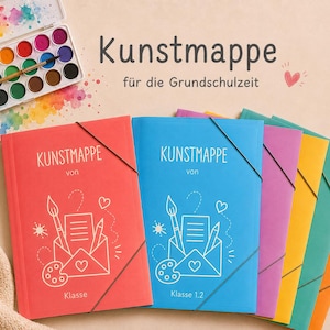 Könnte beinhalten: Ein Set bunter Kunstmappen mit Gummizugverschluss, beschriftet mit Kunstmappe, verziert mit einer weißen Strichzeichnung aus Umschlag, Pinsel, Stift und Palette. Ein Aquarellfarbkasten mit Pinsel liegt oberhalb der Mappen.