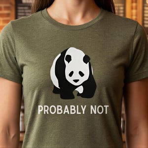 Op de afbeelding: Olijfgroen t-shirt met een zwart-wit panda ontwerp. De tekst "PROBABLY NOT" staat eronder in het wit gedrukt. Het t-shirt heeft korte mouwen en een ronde hals.