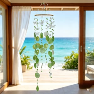 May include: A hanging mobile featuring a circular frame with multiple strands of green circular discs, clear butterfly-shaped ornaments, and small green beads. The decorative piece is suspended by thin wires, creating a cascading arrangement of light green and translucent elements that hang vertically from the central ring structure.