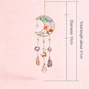 May include: A celestial-themed hanging ornament featuring a crescent moon design. The gold-colored metal frame holds colorful crystals and gemstones, with a total length of about 14.5 inches and a diameter of about 4 inches.