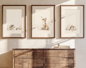May include: Three framed wall art prints featuring watercolor illustrations of woodland animals. The left print shows a hedgehog, the center print depicts a fox looking at a butterfly, and the right print displays a mouse, all set against a cream background.