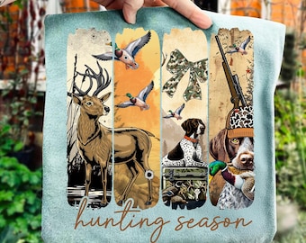 May include: A light blue tote bag featuring a hunting theme. The design includes a deer, ducks, a bow, a dog, a rifle, and the words "hunting season". The artwork is in shades of brown, green, and orange.