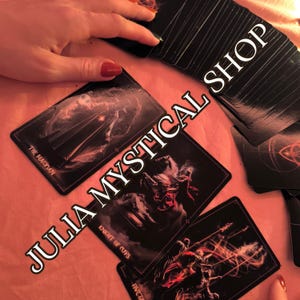 May include: A deck of black tarot cards featuring The Magician, Knight of Cups, and Five of Cups, with the text JULIA MYSTICAL SHOP overlaid. The cards display dark, atmospheric illustrations with red and white highlights on a pink surface.
