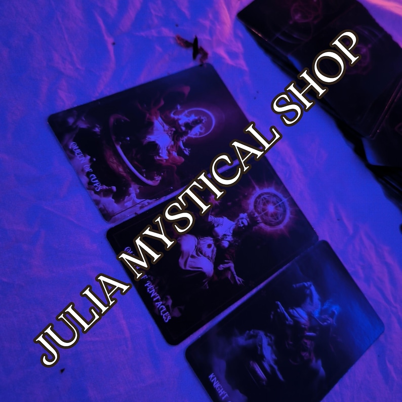 May include: Three rectangular tarot cards with dark, moody illustrations are arranged on a surface. The cards feature the text Queen of Cups, Ace of Pentacles, and Knight of Swords. The text JULIA MYSTICAL SHOP is overlaid diagonally across the image.