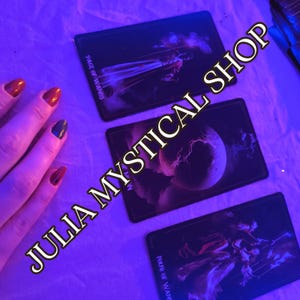 May include: Three rectangular tarot cards arranged on a surface under blue lighting. The cards are labeled Page of Wands, The Moon, and Four of Wands. The text JULIA MYSTICAL SHOP is overlaid diagonally across the image in a bold, dark font.