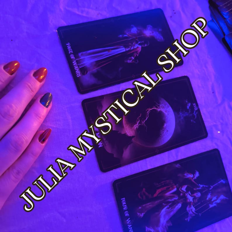 May include: Three rectangular tarot cards arranged on a surface under blue lighting. The cards are labeled Page of Wands, The Moon, and Four of Wands. The text JULIA MYSTICAL SHOP is overlaid diagonally across the image in a bold, dark font.