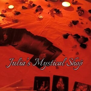 May include: A mystical scene with tarot cards, candles, and rose petals on a red surface. The text "Julia's Mystical Shop" is displayed. The image evokes a sense of divination and spirituality.