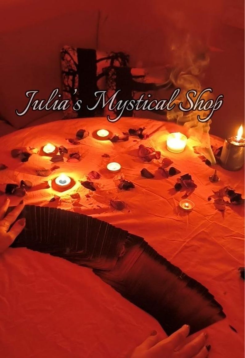 May include: An orange-red scene with lit candles, rose petals, and a deck of cards. The text "Julia's Mystical Shop" is displayed in a cursive font. Smoke rises from the scene, creating a mystical atmosphere.