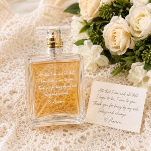 May include: A rectangular glass perfume bottle filled with amber liquid, featuring white engraved text that reads: All that I am and all that I hope to be, I owe to you. Thank you for being by my side. Today and always. ♡ Aurora.