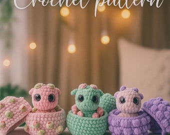 May include: Crochet pattern image featuring three small, colorful crochet dragons in baskets. The dragons are pink, green, and purple, with matching baskets. The text "Crochet pattern" is written in cursive at the top of the image.