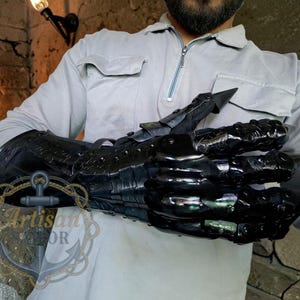 Pu&ograve; includere: Guanto in metallo nero con dita articolate e artigli affilati. Il guanto &egrave; indossato sul braccio e presenta dettagli intricati e una finitura lucida. Il design ricorda un artiglio di drago, perfetto per cosplay o appassionati di fantasy.