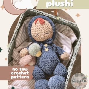 May include: A handmade blue crochet plushie doll with a tan face and red hair, resting in a woven basket. The doll has button details and a pom-pom accessory. Text on the image reads "bubs plushi" and "no sew crochet pattern".