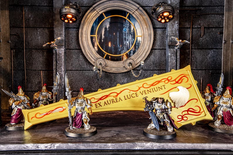 Peut inclure: Figurines miniatures de guerriers en armure avec &eacute;p&eacute;es et lances. Une grande banni&egrave;re jaune avec des accents rouges et du texte est au centre. L'arri&egrave;re-plan pr&eacute;sente une fen&ecirc;tre circulaire et un &eacute;clairage d&eacute;coratif.