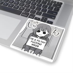 以下が含まれることがあります： 正方形のステッカー。白黒のアニメスタイルのイラストで、女の子が看板を持っています。看板には「I'M A FILTHY FUCKING WEEB」と書かれています。ステッカーはラップトップに貼られています。