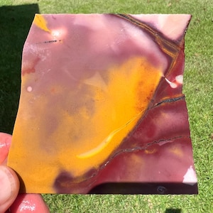 May include: A flat, polished slab of Mookaite jasper featuring a vibrant color palette of deep burgundy, mustard yellow, and soft cream. The stone displays natural swirling patterns, organic color transitions, and thin dark mineral veins.