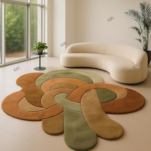 Op de afbeelding: Een moderne woonkamer met een groot, abstract gevormd tapijt in bruin- en groentinten. Op de achtergrond staat een gebogen, crèmekleurige bank. De kamer heeft grote ramen en een minimalistisch design.