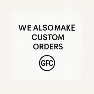 May include: White square with black text that reads "WE ALSO MAKE CUSTOM ORDERS". Below the text is a circular logo with the letters "GFC" inside.