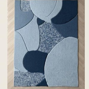 May include: A rectangular blue rug with an abstract design. The rug features various shades of blue, including light, medium, and dark tones, arranged in organic shapes. The word "Blue" is printed at the bottom of the image.