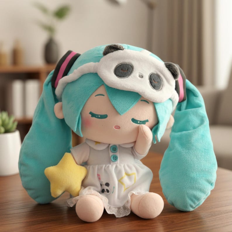 May include: A plush doll with turquoise hair and a panda eye mask. The doll wears a white dress with a star and panda design and holds a yellow star. The doll is sitting with its eyes closed.
