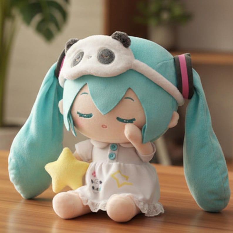 May include: A plush doll with light blue hair and a panda eye mask. The doll wears a white dress and holds a yellow star. The doll has closed eyes and is sitting on a wooden surface.