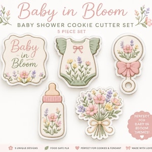 Może przedstawiać: Zestaw 5 foremek do ciastek z motywami dziecięcymi, zawierający tabliczkę z napisem Baby in Bloom, śpioszki, grzechotkę, butelkę dla niemowląt i bukiet kwiatów. Każdy element jest ozdobiony pastelowymi ilustracjami kwiatowymi w kolorze różowym, żółtym i zielonym.