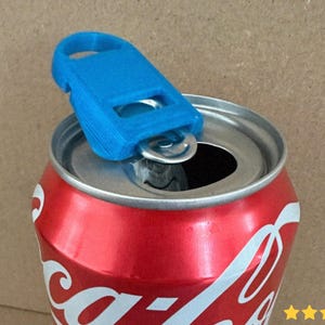 May include: A blue can opener is placed on top of a red soda can. The can opener is made of plastic and has a loop for easy handling. The soda can has white text and is partially opened.
