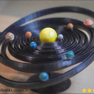 Könnte beinhalten: Ein schwarzes, 3D-gedrucktes Modell des Sonnensystems. Das Modell zeigt eine gelbe Sonne im Zentrum, umgeben von spiralförmigen Bahnen mit farbenfrohen Planetenrepliken. Die Basis ist dunkel, und die Planeten sind in verschiedenen Größen und Farben.