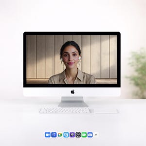 May include: A white iMac computer with a black screen displaying a woman wearing a tan shirt and white earbuds. A white keyboard and trackpad are in front of the computer. The background is a light wood panel wall.