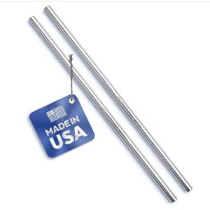 Könnte beinhalten: Zwei gerade Trinkhalme aus poliertem Edelstahl. An einem Halm ist mit einer dünnen grauen Schnur ein quadratisches blaues Etikett befestigt, das ein weißes US-Flaggen-Symbol und den Text "MADE IN USA" in weißen Großbuchstaben zeigt.