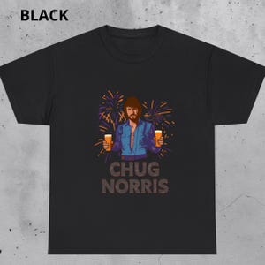 May include: Black t-shirt featuring a cartoon illustration of a man holding two mugs of beer, with fireworks in the background. The text "CHUG NORRIS" is printed below the image. The word "BLACK" is printed at the top.