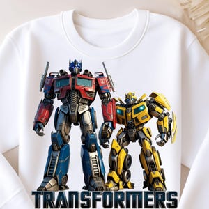 Può includere: Felpa girocollo bianca con grafica di Optimus Prime e Bumblebee dei Transformers. Optimus Prime è rosso, blu e argento. Bumblebee è giallo e nero. La parola "TRANSFORMERS" è stampata in nero in basso.