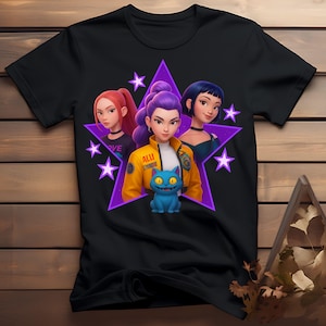 Può includere: T-shirt nera con grafica di tre figure femminili stilizzate all'interno di una stella viola, con un gatto blu. La figura centrale indossa una giacca gialla. La parola "LOVE" è visibile.