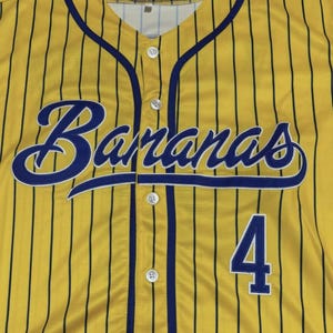 May include: A yellow baseball jersey with thin vertical black pinstripes, featuring the word Bananas in a blue script font across the chest and the number 4 in blue block digits below. The shirt has a button-down front with white buttons.