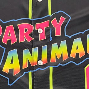 May include: A black button-down jersey featuring the text PARTY ANIMALS in a pink and rainbow gradient font with a light blue outline. The jersey includes vertical neon yellow piping, white buttons, and the number 07 in neon pink and yellow.