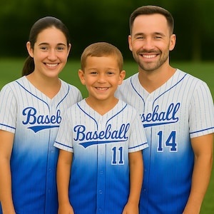 May include: Three people wearing baseball jerseys. The jerseys are white with blue pinstripes and a blue gradient at the bottom. The word "Baseball" is printed on the front of the jerseys in blue, along with numbers. The people are smiling.