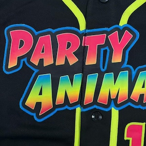 May include: A black button-down baseball jersey featuring neon yellow piping along the placket and collar. The front displays the text PARTY ANIMAL in a gradient of pink, orange, and yellow with a bright blue outline, plus a partial pink number 1.