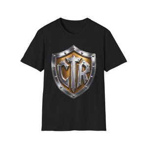 May include: Black crew neck t-shirt featuring a metallic shield design. The shield has a gold center with the letters "CTR" in silver, surrounded by a silver border with rivets. The shirt is made of a soft, comfortable material.