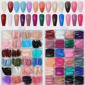 Könnte beinhalten: Eine Sammlung künstlicher Fingernägel in verschiedenen Farben, darunter Rot, Blau, Rosa und neutrale Töne. Das Bild zeigt einzelne Nägel und Sets von Nägeln in einem transparenten Kunststoff-Organizer.