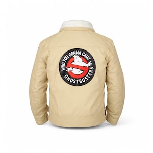 May include: Tan jacket with a white faux fur collar and a large Ghostbusters logo on the back. The logo features the Ghostbusters symbol with the text "WHO YOU GONNA CALL?" and "GHOSTBUSTERS" in a circular design.