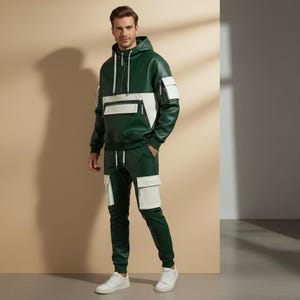 May include: A green and white hooded sweatshirt and matching pants set. The sweatshirt has a white panel across the chest and white pockets. The pants have white pockets on the thighs. The outfit is made of a leather-like material and is paired with white sneakers.