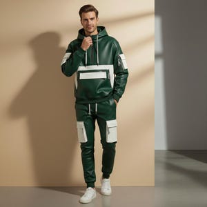 May include: Green and white faux leather hooded sweatshirt and matching pants. The sweatshirt has a white panel across the chest and white stripes on the sleeves. The pants have white pockets. The outfit is paired with white sneakers.