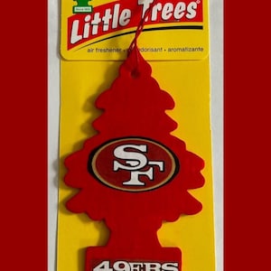 Puede incluir: Ambientador Little Trees rojo con forma de árbol de Navidad, con el logotipo de los 49ers de San Francisco. El ambientador está sobre un fondo amarillo con las palabras "Little Trees" y "49ERS" impresas.