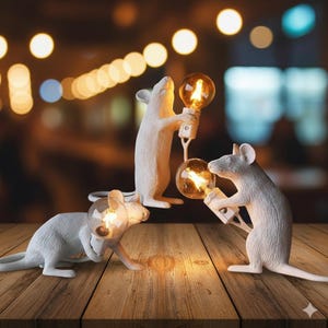 以下が含まれることがあります： 白とグレーのネズミの形をしたランプが3つ。それぞれ電球を持っています。 ランプは木製の表面にあり、背景はぼやけた暖色の光です。 ネズミはさまざまなポーズをとっています。