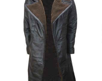 May include: A long, black leather coat with a brown shearling collar and lining. The coat features a notched lapel, a zipper pocket on the chest, and a long, flowing design. The coat is designed to be worn open.
