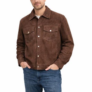 May include: A brown suede jacket with two chest pockets and silver button closures. The jacket has a classic collar and is worn over a white t-shirt and blue jeans. The jacket is a casual outerwear piece.