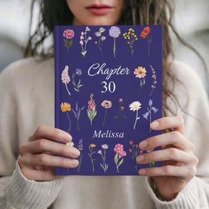 May include: A navy blue book cover featuring floral illustrations and the text "Chapter 30" and "Melissa". The cover is adorned with various colorful flower drawings.