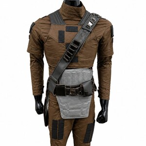 May include: Brown costume with black detailing, featuring a shoulder strap, chest armour, and belt. The costume has a high collar and short sleeves. The outfit is displayed on a mannequin with black gloves.