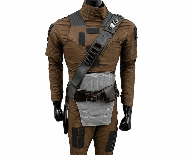 May include: Brown costume with black detailing, featuring a shoulder strap, chest armour, and belt. The costume has a high collar and short sleeves. The outfit is displayed on a mannequin with black gloves.