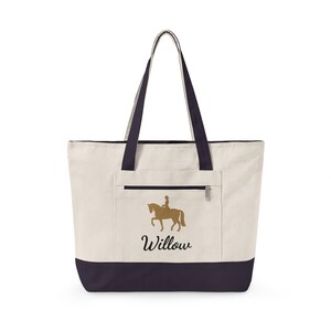 Cream-colored tote bag with navy blue accents. Features a gold silhouette of a horse and rider, with the name "Willow" in script. Includes a zippered pocket and navy blue handles.