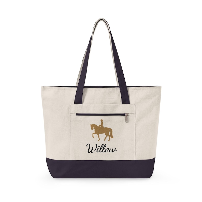 Cream-colored tote bag with navy blue accents. Features a gold silhouette of a horse and rider, with the name "Willow" in script. Includes a zippered pocket and navy blue handles.